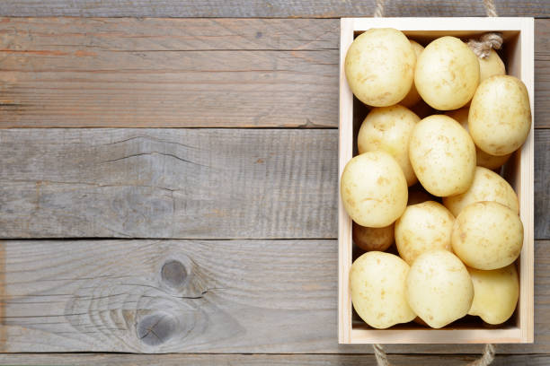 istock Raw potatoes in box on wooden table 974708612