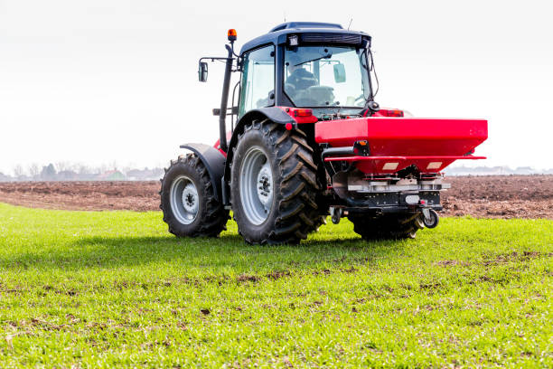 istock Farmer in tractor fertilizing wheat field at spring with npk 974713800