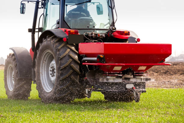 istock Farmer in tractor fertilizing wheat field at spring with npk 974716330