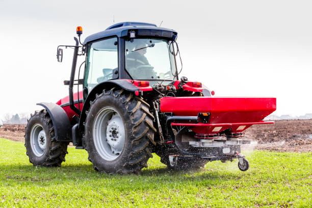 istock Farmer in tractor fertilizing wheat field at spring with npk 974718432