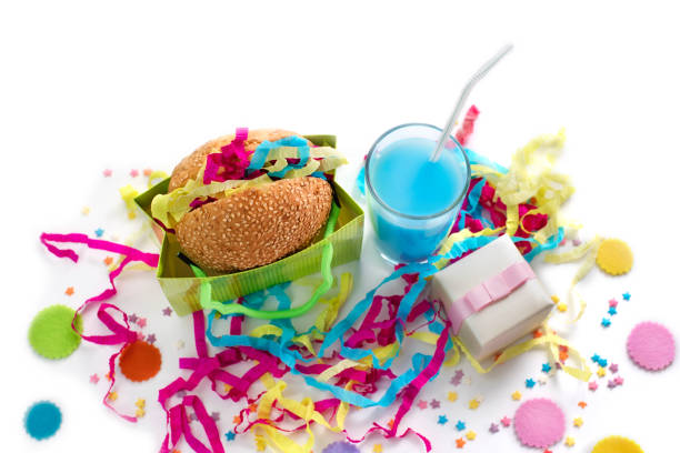 Festive composition drinks snacks holiday hamburger cookie tinsel confetti gift box cocktail saturated colors.