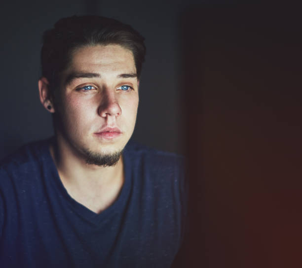 istock Young man sitting in dark staring at his computer 974718862
