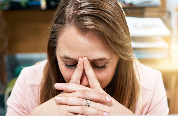 istock Blonde office worker holds head, looking tired, in pain 974719056