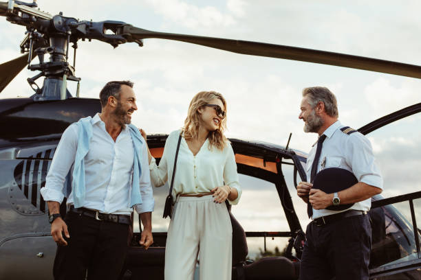 Couple alighted from a helicopter thanking pilot Smiling couple alighted from a private helicopter talking to the pilot. Couple getting off a private aircraft with mature pilot. exclusive travel stock pictures, royalty-free photos & images