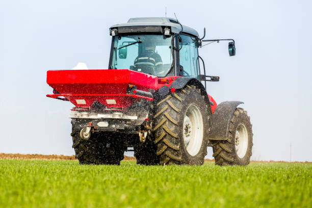 istock Farmer in tractor fertilizing wheat field at spring with npk 974723190