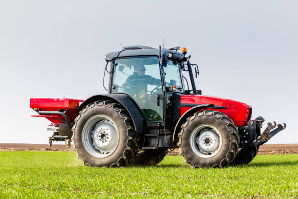 istock Farmer in tractor fertilizing wheat field at spring with npk 974725998