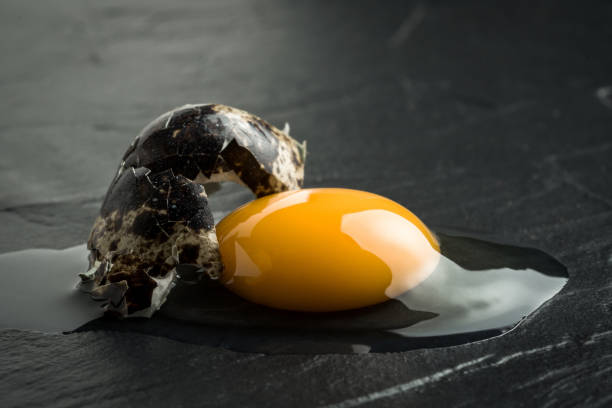 istock Raw Broken Egg Yolk on Dark Stone Background. Fresh Organic Food Concept. 974741498