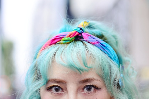 Portrait of a woman with brightly green/blue hair and colourful clothes.