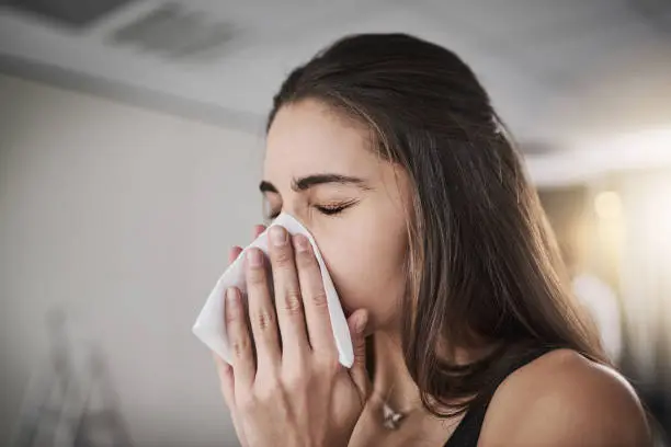 Shot of a young woman blowing her nose