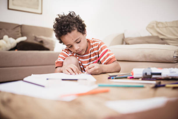 istock Cute mixed - race boy drawing at home 974795108