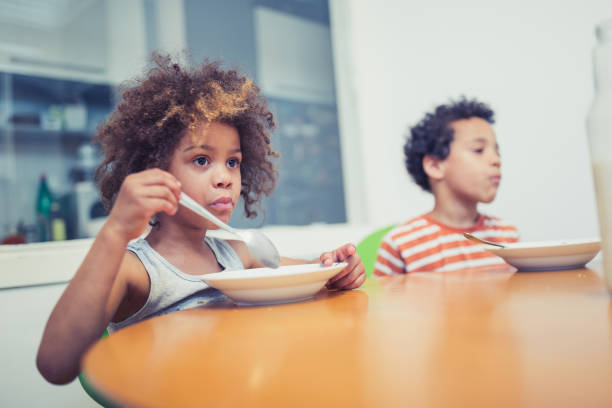 istock Cute mixed - race siblings having breakfast at home 974797562