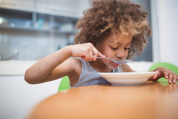 istock Cute mixed - race girl having breakfast at home 974797592