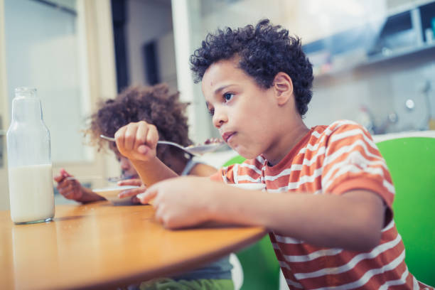 istock Cute mixed - race siblings having breakfast at home 974797612