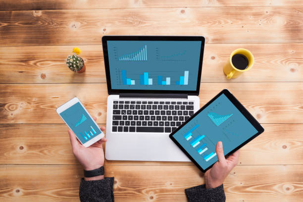 istock Smartphone, tablet pc and a laptop with infographic screen on wooden desk 974805754