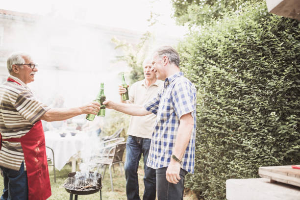 istock Mature male friends having beer while barbecuing at backyard 974806964