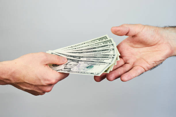 Business closeup of two hands exchanging dollars on grey background. Business closeup of two hands exchanging dollars on grey background. borrowing stock pictures, royalty-free photos & images