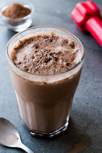 istock Chocolate Protein Shake Smoothie with Whey Protein Powder and Red Dumbbells 974819918