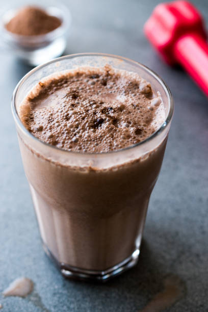 istock Chocolate Protein Shake Smoothie with Whey Protein Powder and Red Dumbbells 974820242
