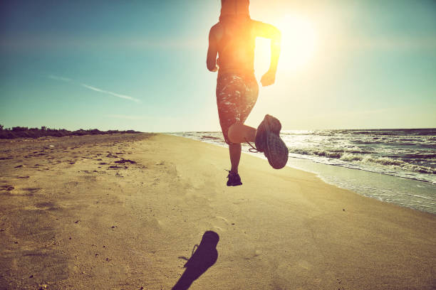 Fitness woman running by the beach at sunrise. Healthy active lifestyle girl exercising outdoors stock photo