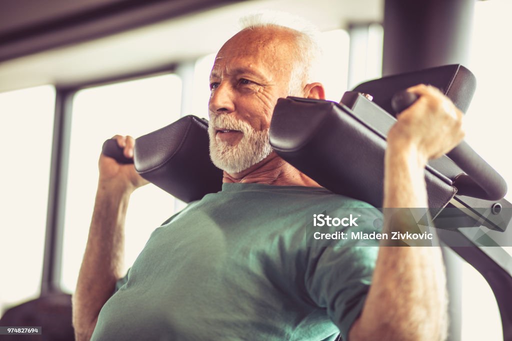 Hard exercise. Active senior man using weights machine in the gym Senior Adult Stock Photo