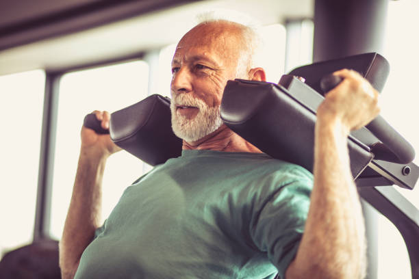 Hard exercise. Active senior man using weights machine in the gym senior bodybuilders stock pictures, royalty-free photos & images