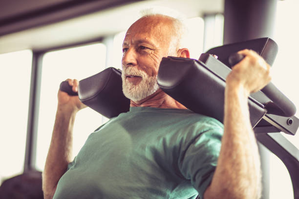 Hard exercise. Active senior man using weights machine in the gym man muscular chest stock pictures, royalty-free photos & images