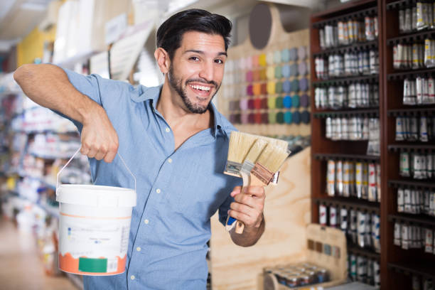 istock Cheerful man choosing brushes and varnishes 974847238