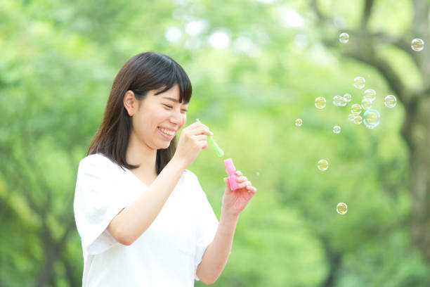 istock A woman blowing soap bubbles in fresh green 974853960