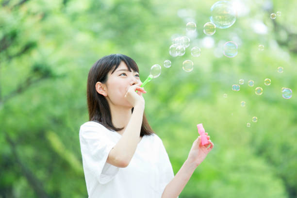 istock A woman blowing soap bubbles in fresh green 974854020
