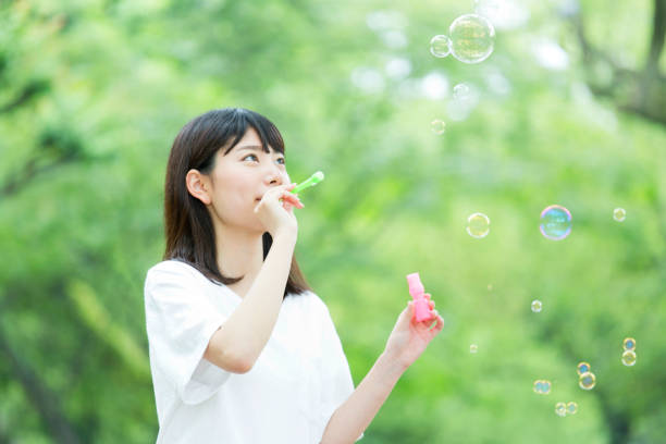 istock A woman blowing soap bubbles in fresh green 974854034
