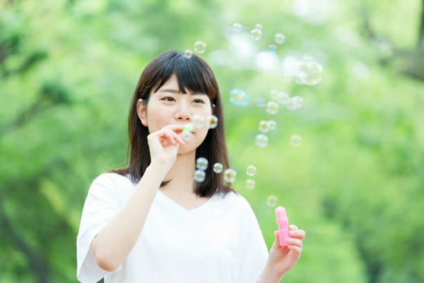 istock A woman blowing soap bubbles in fresh green 974854054