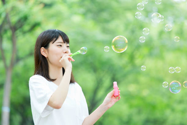 istock A woman blowing soap bubbles in fresh green 974854064