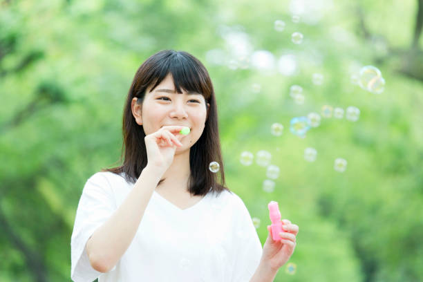 istock A woman blowing soap bubbles in fresh green 974854294