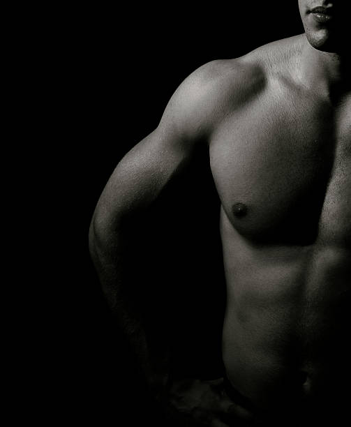 Muscular man in black and white shadow on a black background stock photo