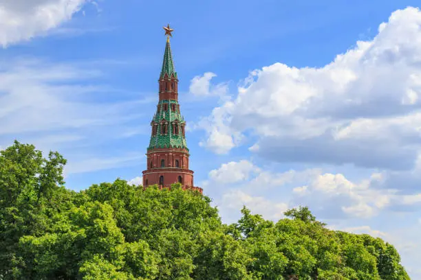 Photo of Vodovzvodnaya tower of Moscow Kremlin on a green trees and blue sky background in sunny summer day