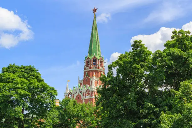 Photo of Armory tower of Moscow Kremlin on a green trees and blue sky background in sunny summer day