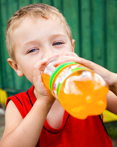 Child drinking unhealthy bottled soda stock photo