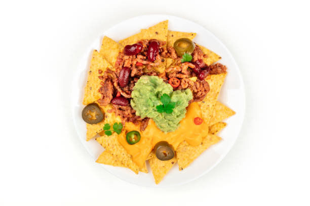 Mexican nachos with beef, guacamole, cheese sauce, peppers, tomato and onion in plate isolated on white background