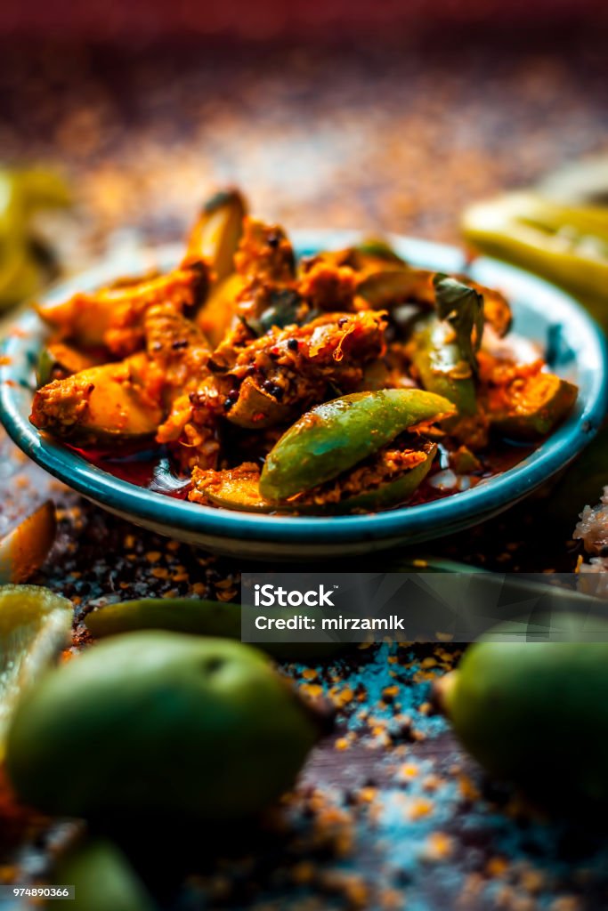 Close Up Of Aam Ka Achar Or Kari Ka Achar Or Traditional Raw Mango Pickle  With All Its Ingredients And Speiceis On A Wooden Surface In Drak Gothic  Colors Stock Photo -