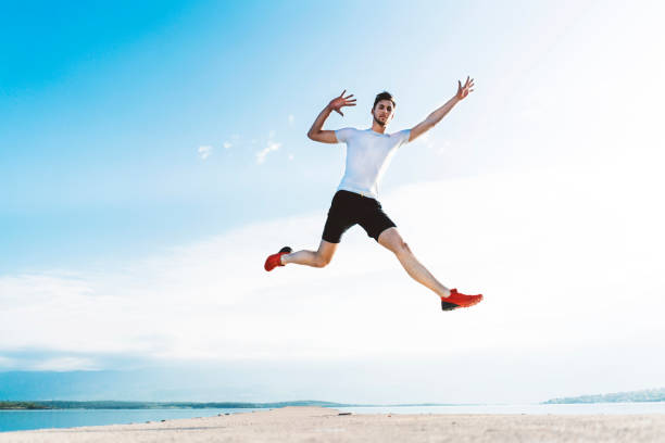 istock Happy man jumping by the sea 974891802