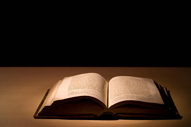 istock Old book open on wooden surface isolated on black background 97494917