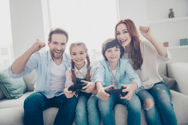 istock Portrait of cheerful brother and sister playing x-box using console controller active mom dad with raised fists celebrating victory shouting enjoying video game. Motivation inspiration concept 974968000