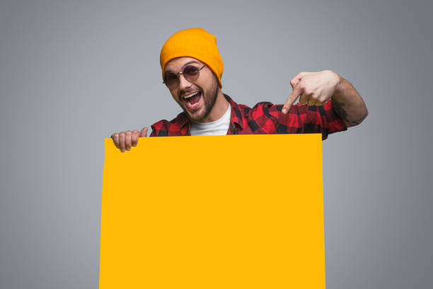 Trendy man pointing at yellow poster