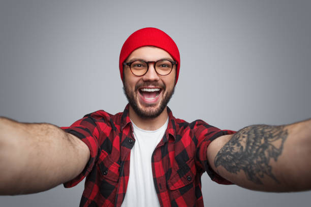 istock Excited trendy man taking selfie on gray 974968688