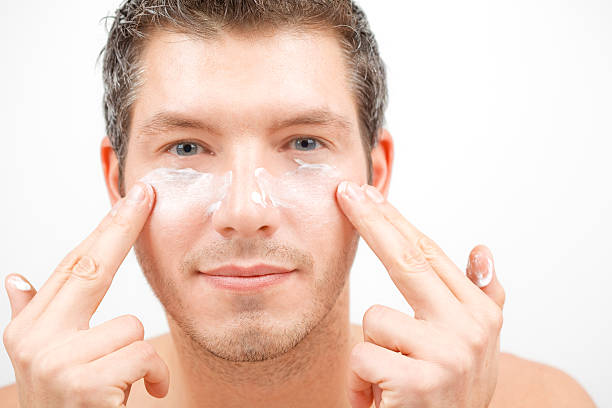 Person applying face lotion for the skin Pretty attractive man beautify applying rejuvenate cream on face for better male macho appearence creaming stock pictures, royalty-free photos & images