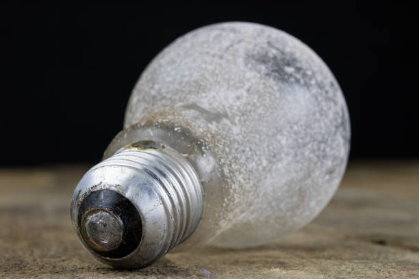 Light bulb lying on a wooden table. Lighting accessories in the old binding. Dark background.