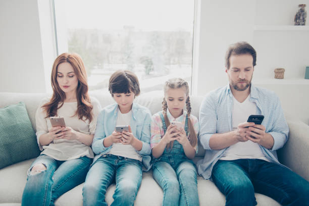 wi-fi 3 g インター ネット チェック メール連絡先を検索を使用してテキスト メッセージ sms を手で電子デバイスを持つスマート フォンを保持している 2 人の子供を持つ家族の肖像画。アプリ� - 依存症 ストックフォトと画像