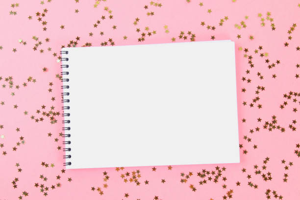 istock An empty pad on a pastel background surrounded by shiny decorative stars and balls. 975025900
