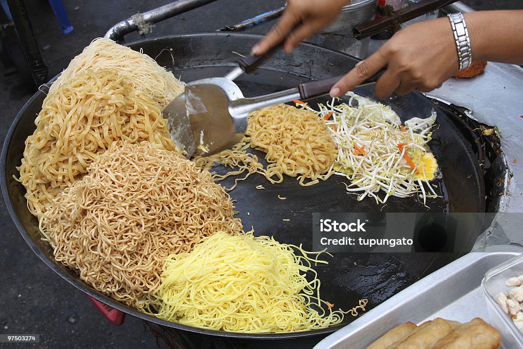 Chef making a serving of fresh stir fry and wok Preparing pad thai at a street hawker mobile restaurant in Bangkok, Thailand. Fried noodle. Asia Stock Photo