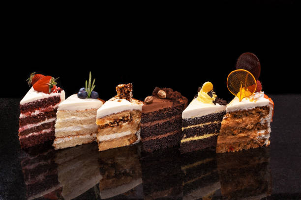 assortiment de gros morceaux de gâteaux différentes : chocolat, fraises, noix, framboises, bleuets. morceaux de gâteaux sur un tableau noir - part de gâteau photos et images de collection